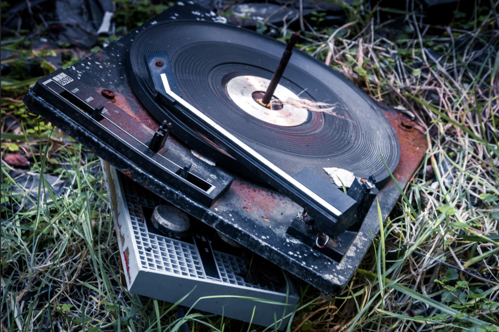 Broken record player decaying over grass